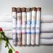 Whole Self Aromatherapy's bath salts in test tubes on a light gray background, with a delicate pink flower and white linens nearby.